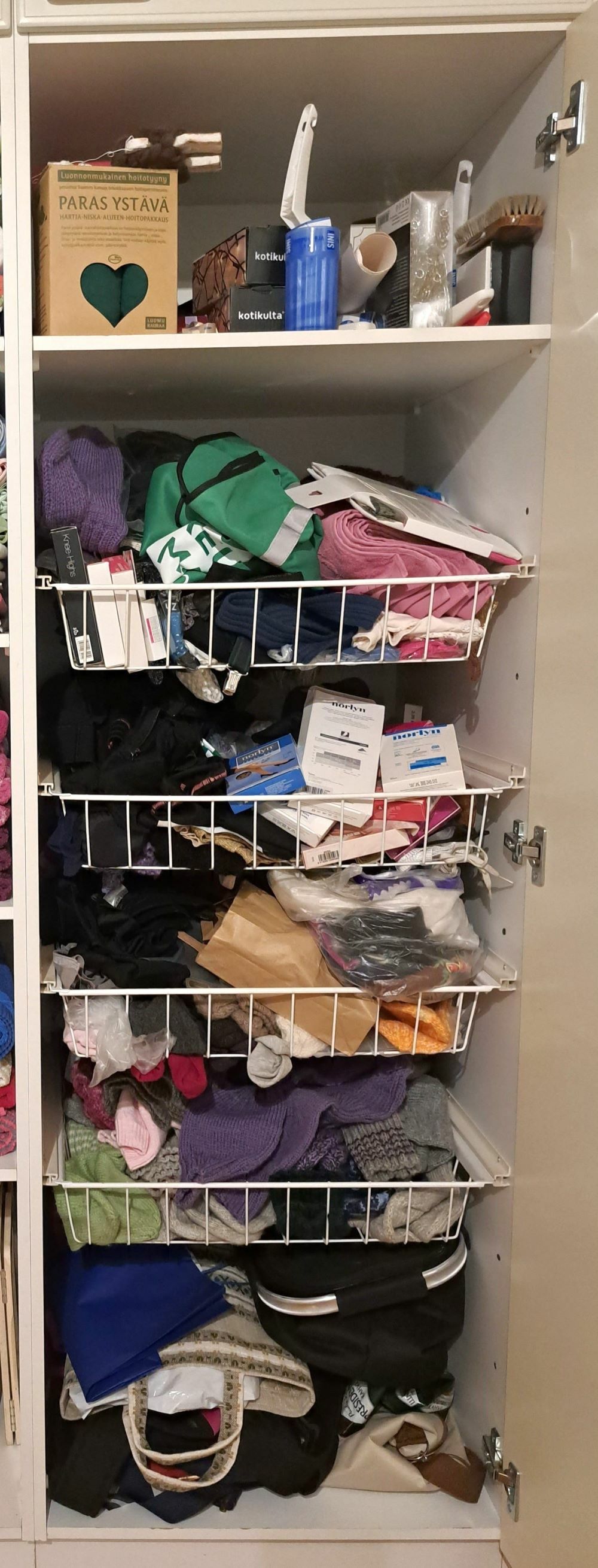 Korikaappi on sekaisin ja täynnä sukkia, kasseja ja muuta tavaraa.