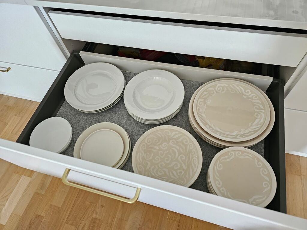 Keittiön vetolaatikon lautaset on järjestetty yhdenmukaisiin pinoihin.